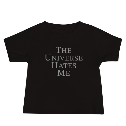 "The Universe Hates Me" printed on a black baby jersey short sleeve tee laying on a flat surface