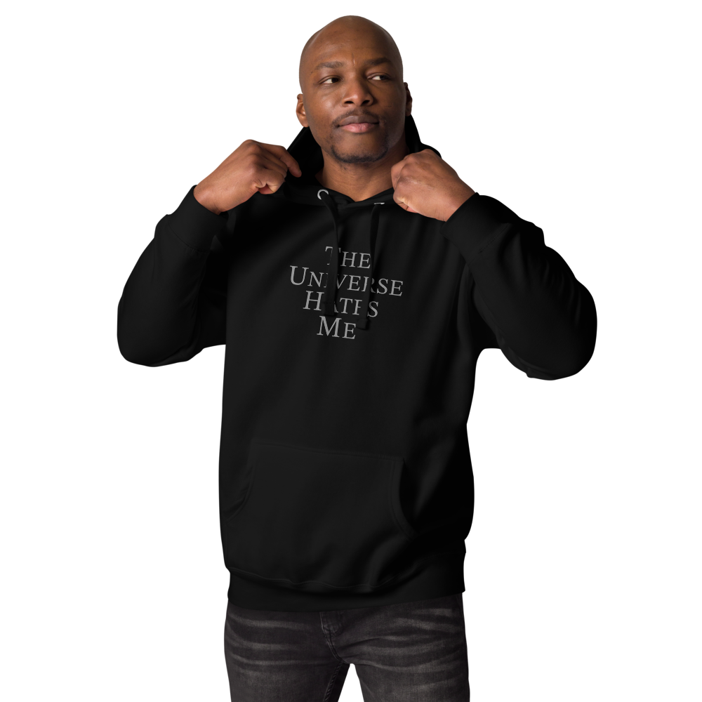 "The Universe Hates Me" printed on a black unisex hoodie worn by a male