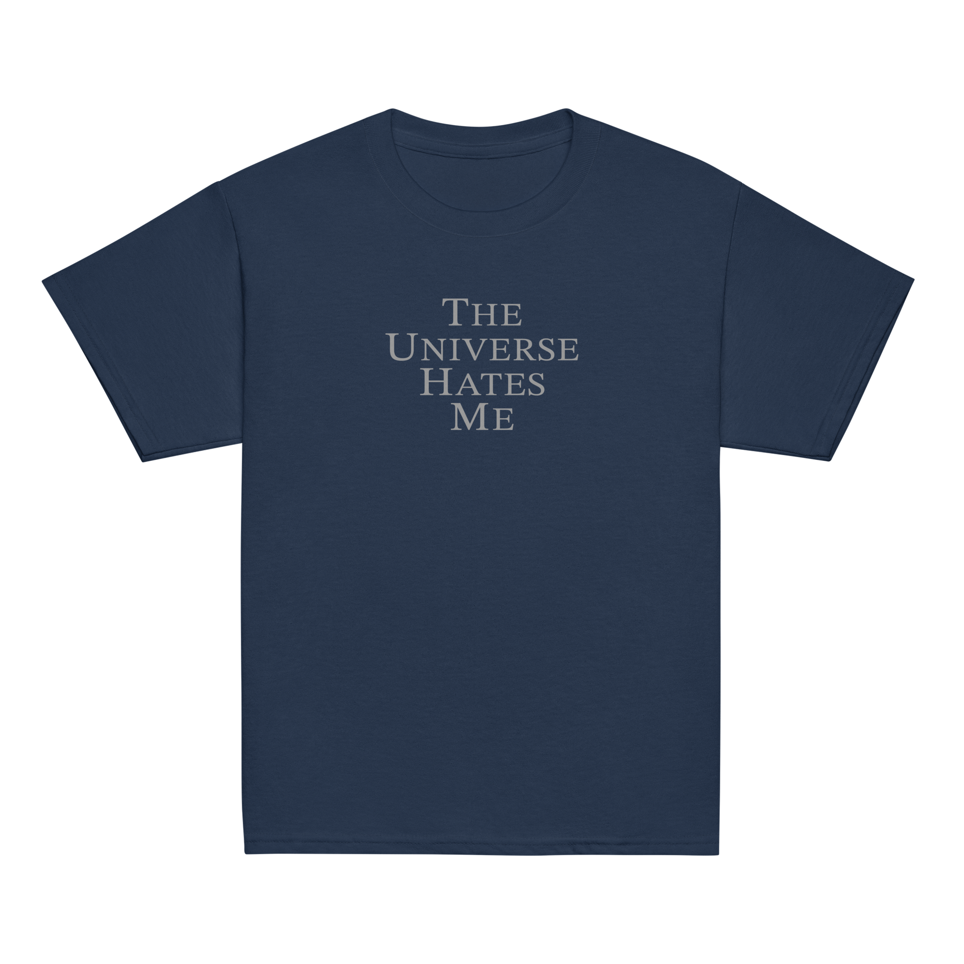 "The Universe Hates Me" printed on a navy youth classic tee laying on a flat surface