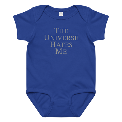 "The Universe Hates Me" printed on a royal baby jersey bodysuit laying on a flat surface amongst other clothes