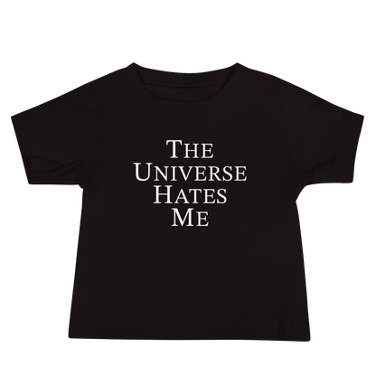 "The Universe Hates Me" printed on a black baby jersey short sleeve tee laying on a flat surface