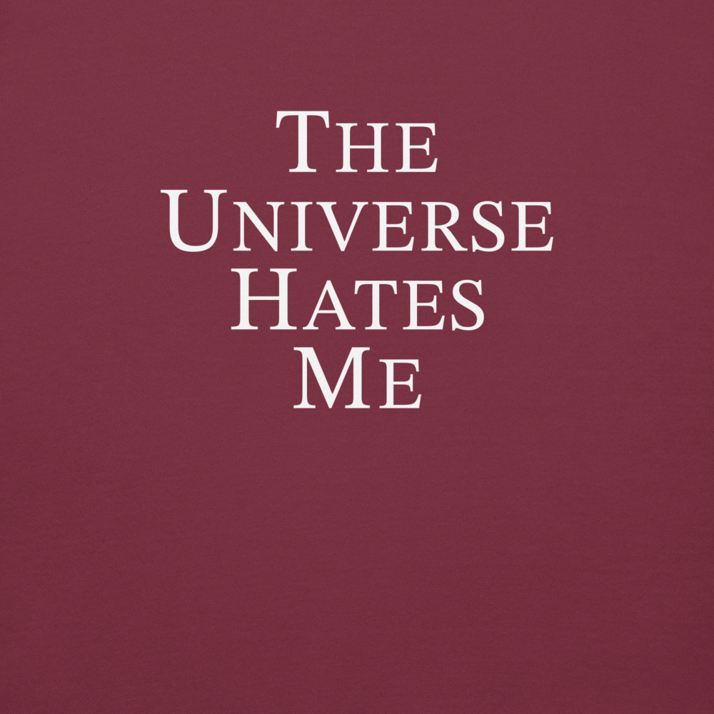 "The Universe Hates Me" printed on a maroon background