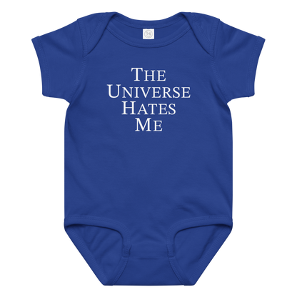 "The Universe Hates Me" printed on a royal baby jersey bodysuit laying on a flat surface amongst other clothes
