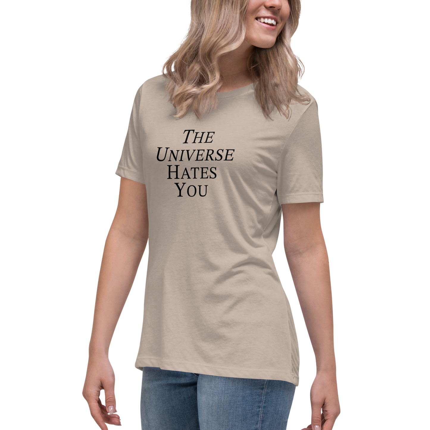 "The Universe Hates You" printed on a heather stone women's relaxed t-shirt worn by a female