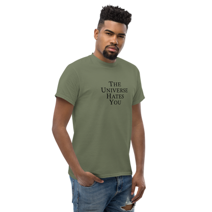 "The Universe Hates You" printed on a military green unisex classic tee worn by a male