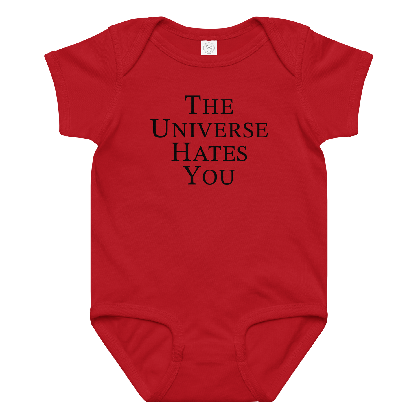 "The Universe Hates You" printed on a red baby jersey bodysuit laying on a flat surface amongst other clothes