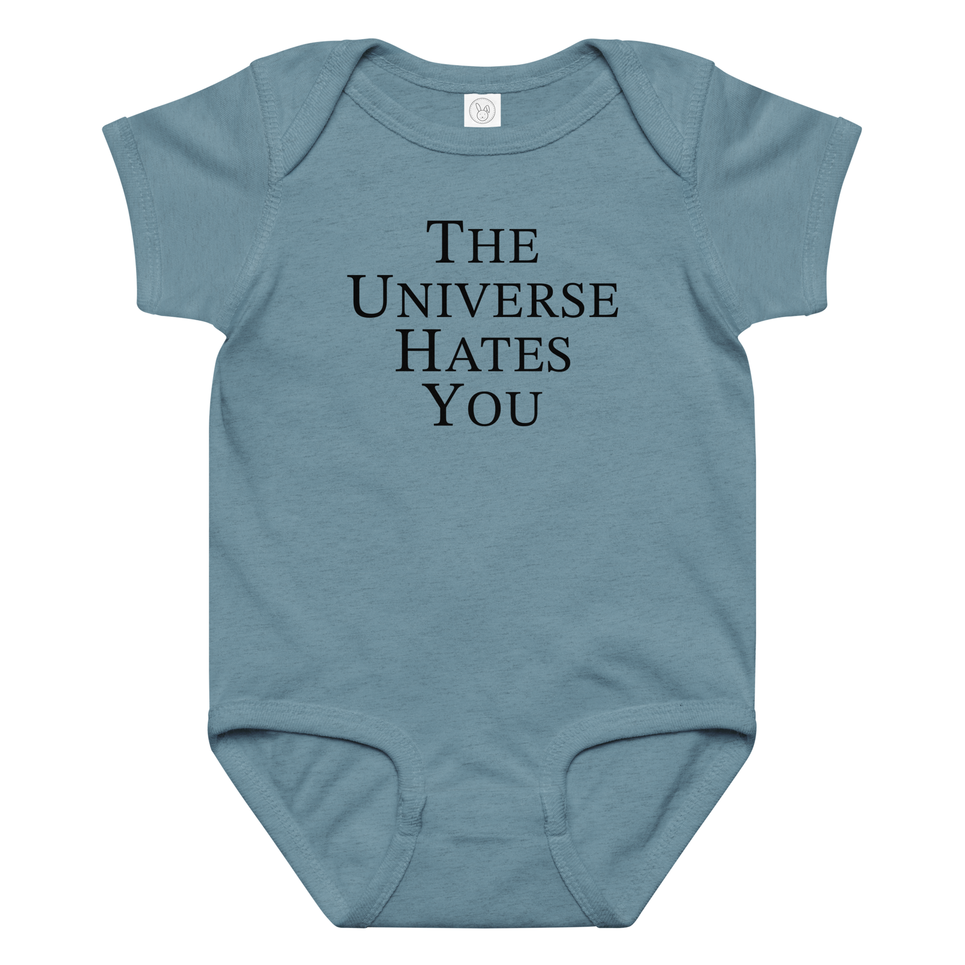 "The Universe Hates You" printed on a vintage indigo baby jersey bodysuit laying on a flat surface amongst other clothes