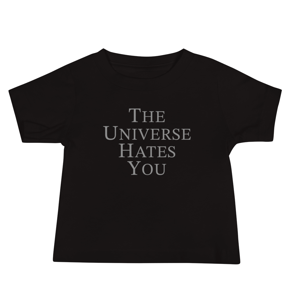 "The Universe Hates You" printed on a black baby jersey short sleeve tee laying on a flat surface