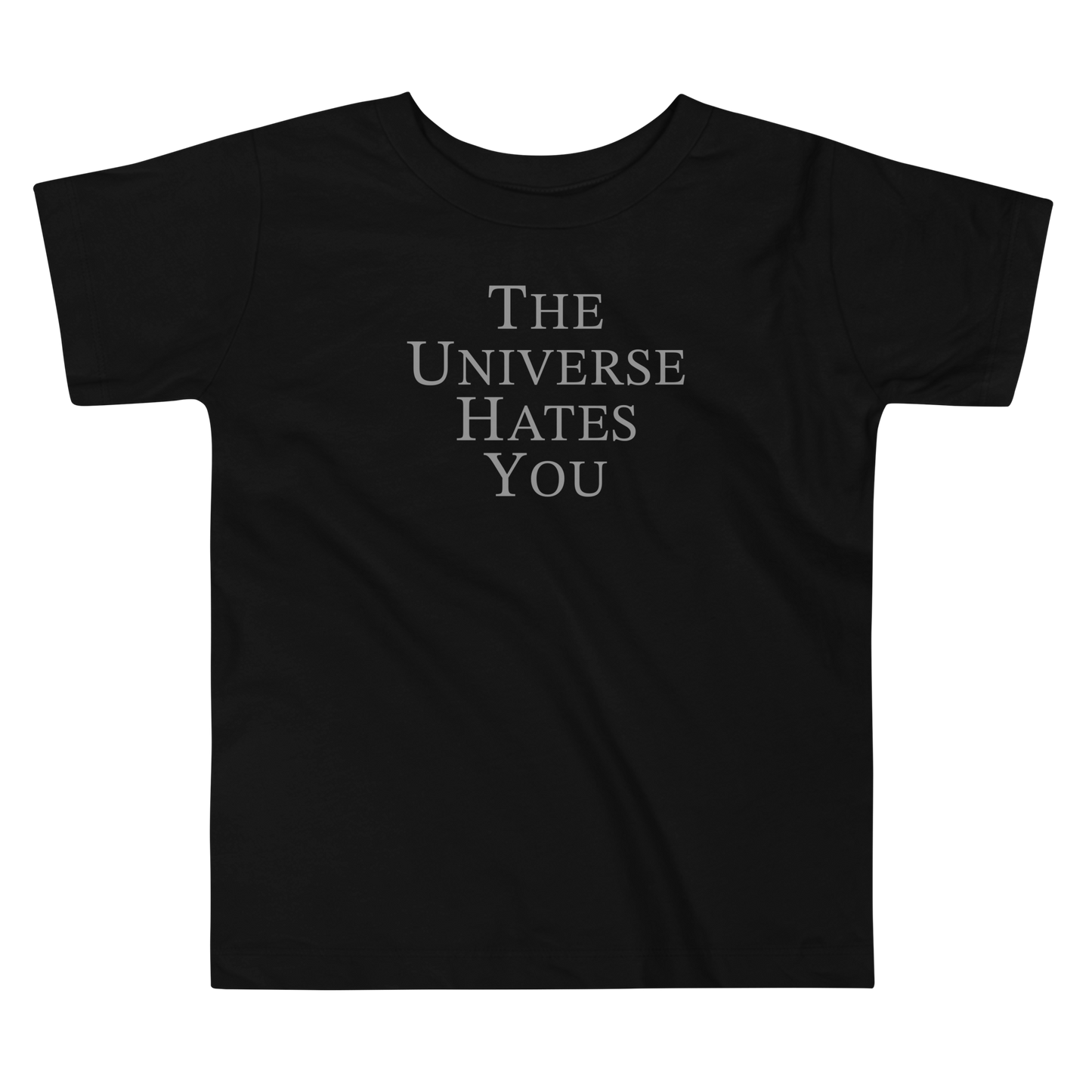 "The Universe Hates You" printed on a black toddler short sleeve tee laying on a flat surface