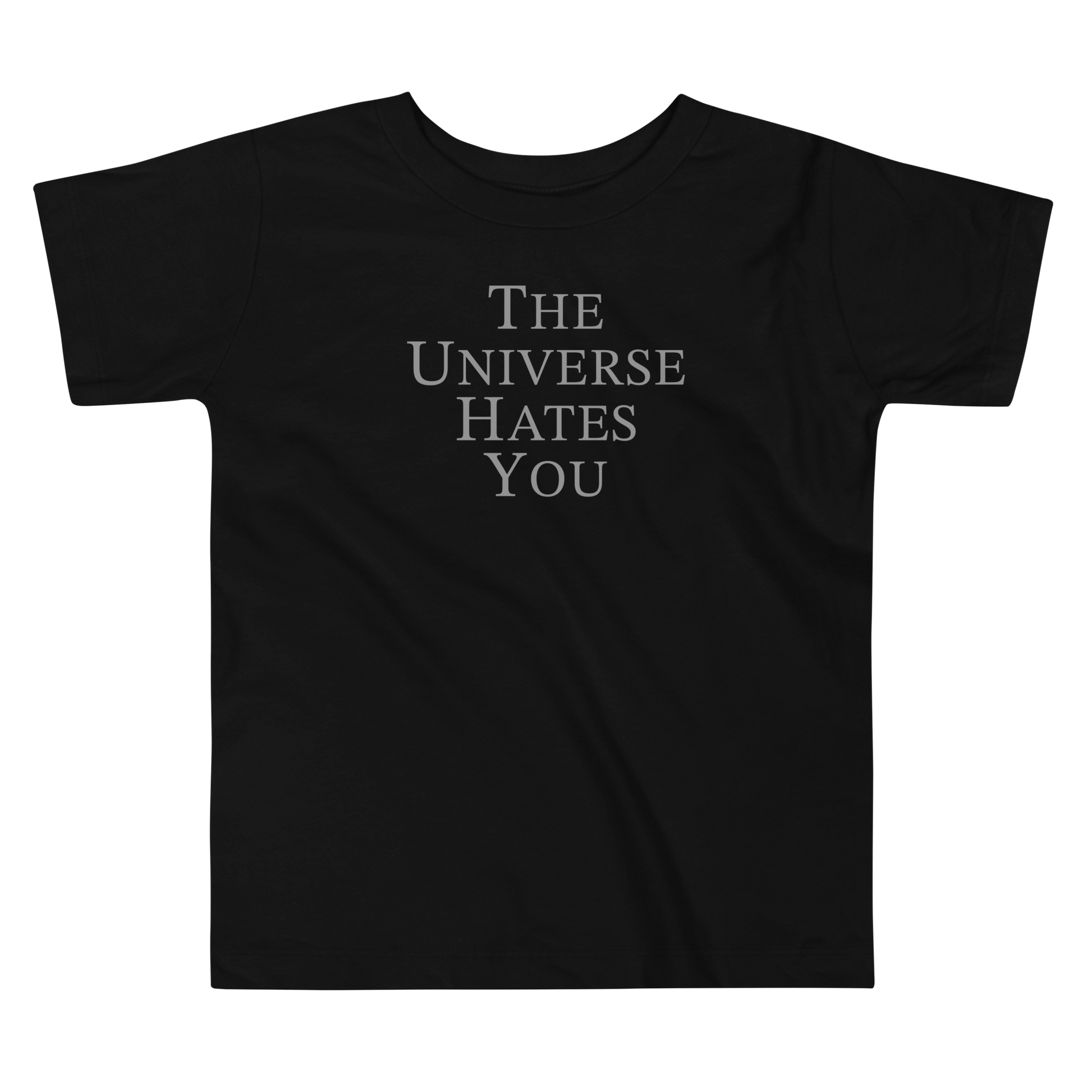 "The Universe Hates You" printed on a black toddler short sleeve tee laying on a flat surface