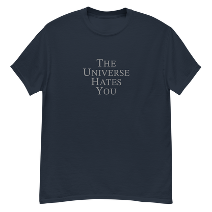 "The Universe Hates You" printed on a navy unisex classic tee laying on a flat surface