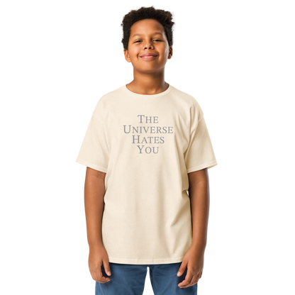 "The Universe Hates You" printed on a natural youth classic tee worn by a male