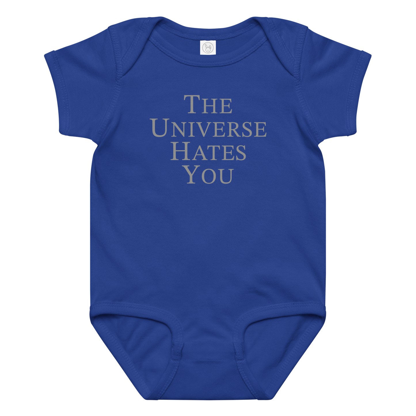 "The Universe Hates You" printed on a royal baby jersey bodysuit laying on a flat surface amongst other clothes