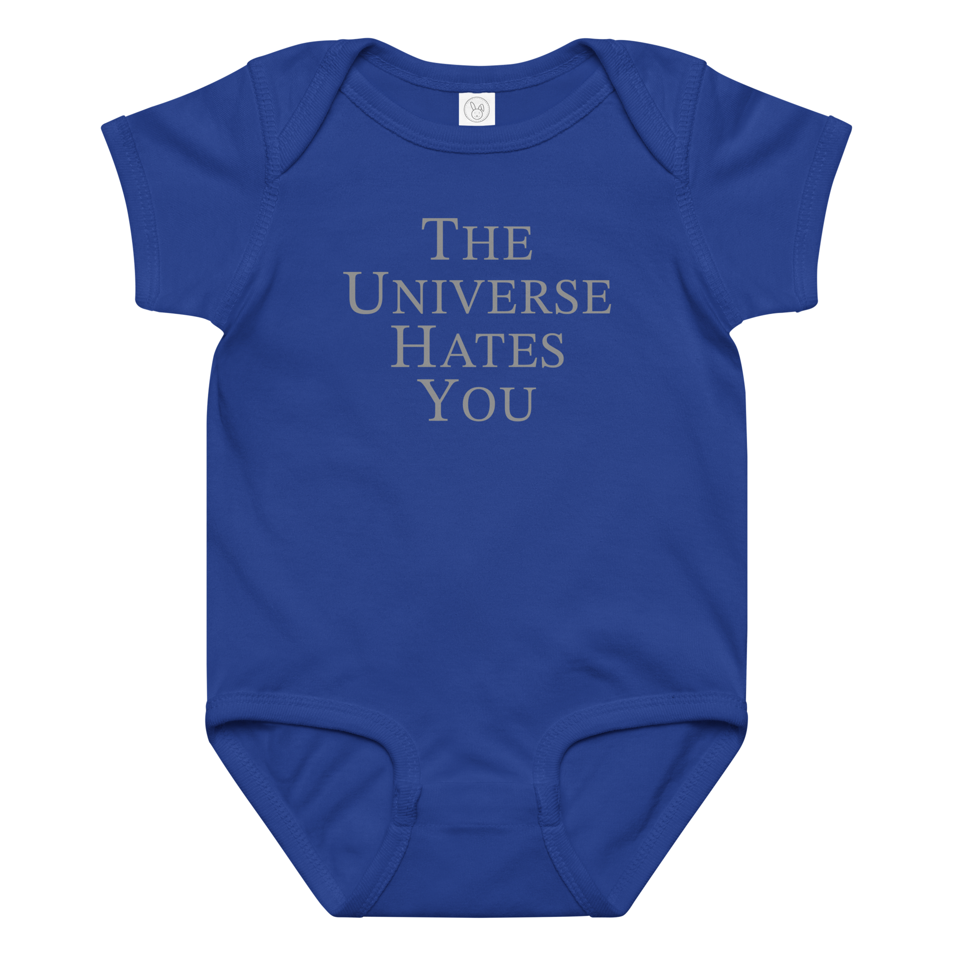 "The Universe Hates You" printed on a royal baby jersey bodysuit laying on a flat surface amongst other clothes