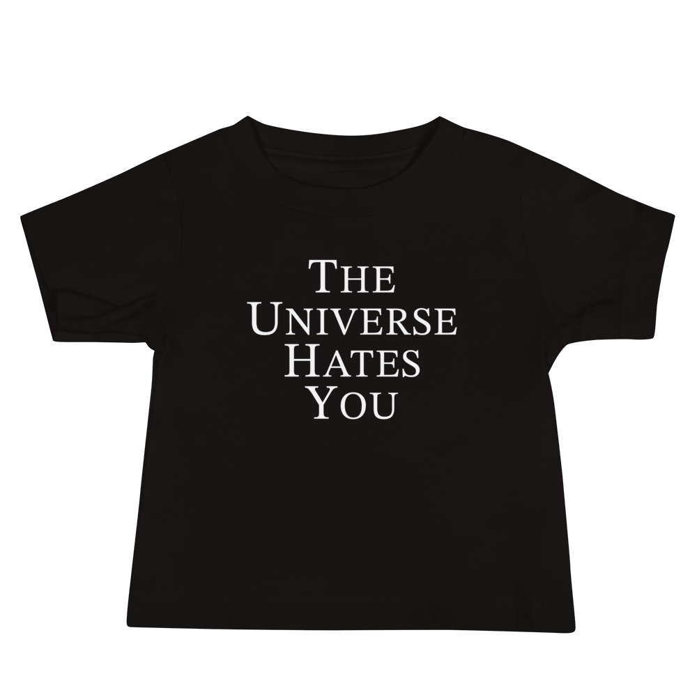 "The Universe Hates You" printed on a black baby jersey short sleeve tee laying on a flat surface
