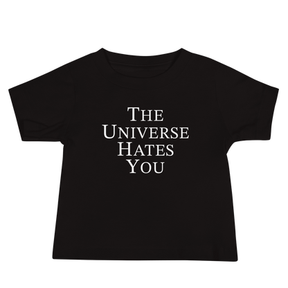 "The Universe Hates You" printed on a black baby jersey short sleeve tee laying on a flat surface