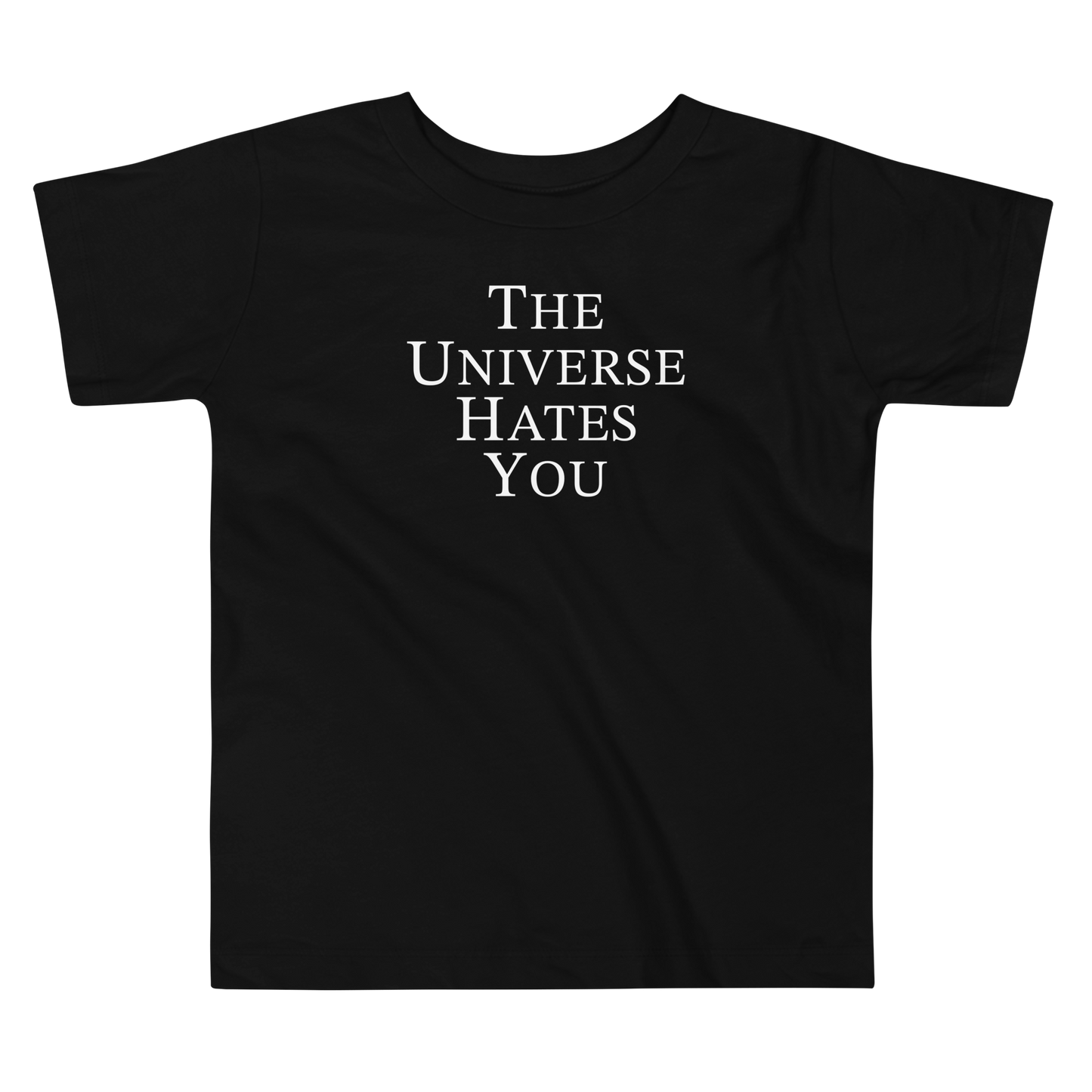 "The Universe Hates You" printed on a black toddler short sleeve tee laying on a flat surface