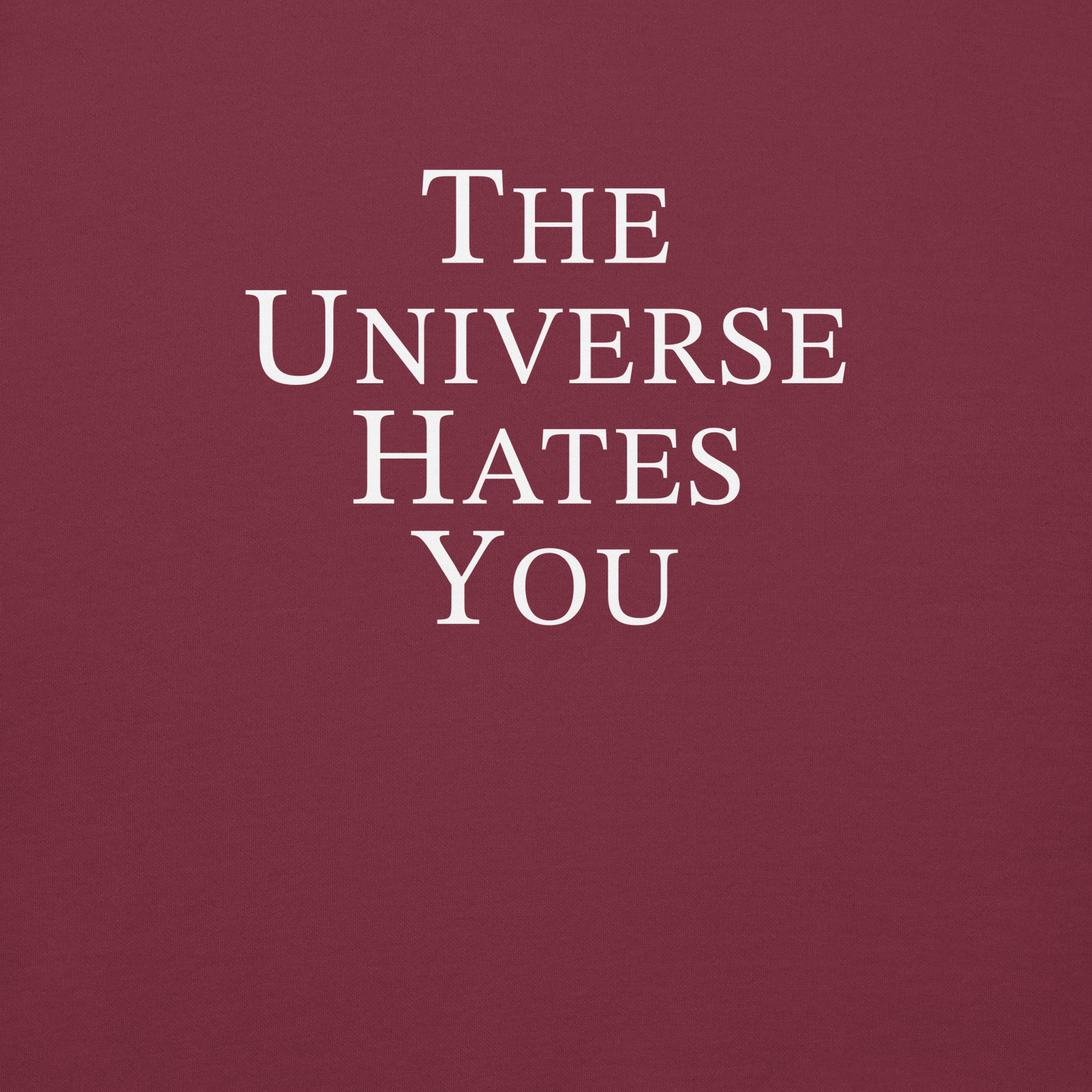 "The Universe Hates You" printed on a maroon background
