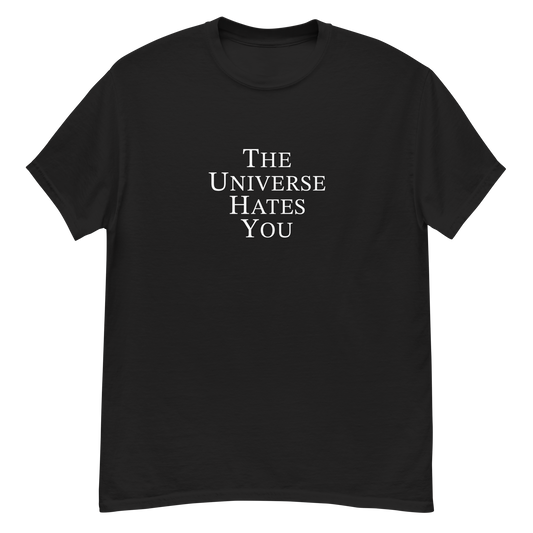 "The Universe Hates You" printed on a black unisex classic tee laying on a flat surface