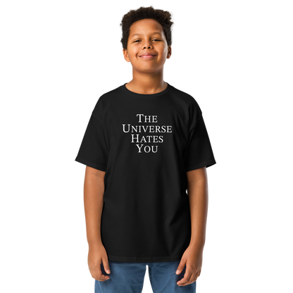 "The Universe Hates You" printed on a black youth classic tee worn by a male