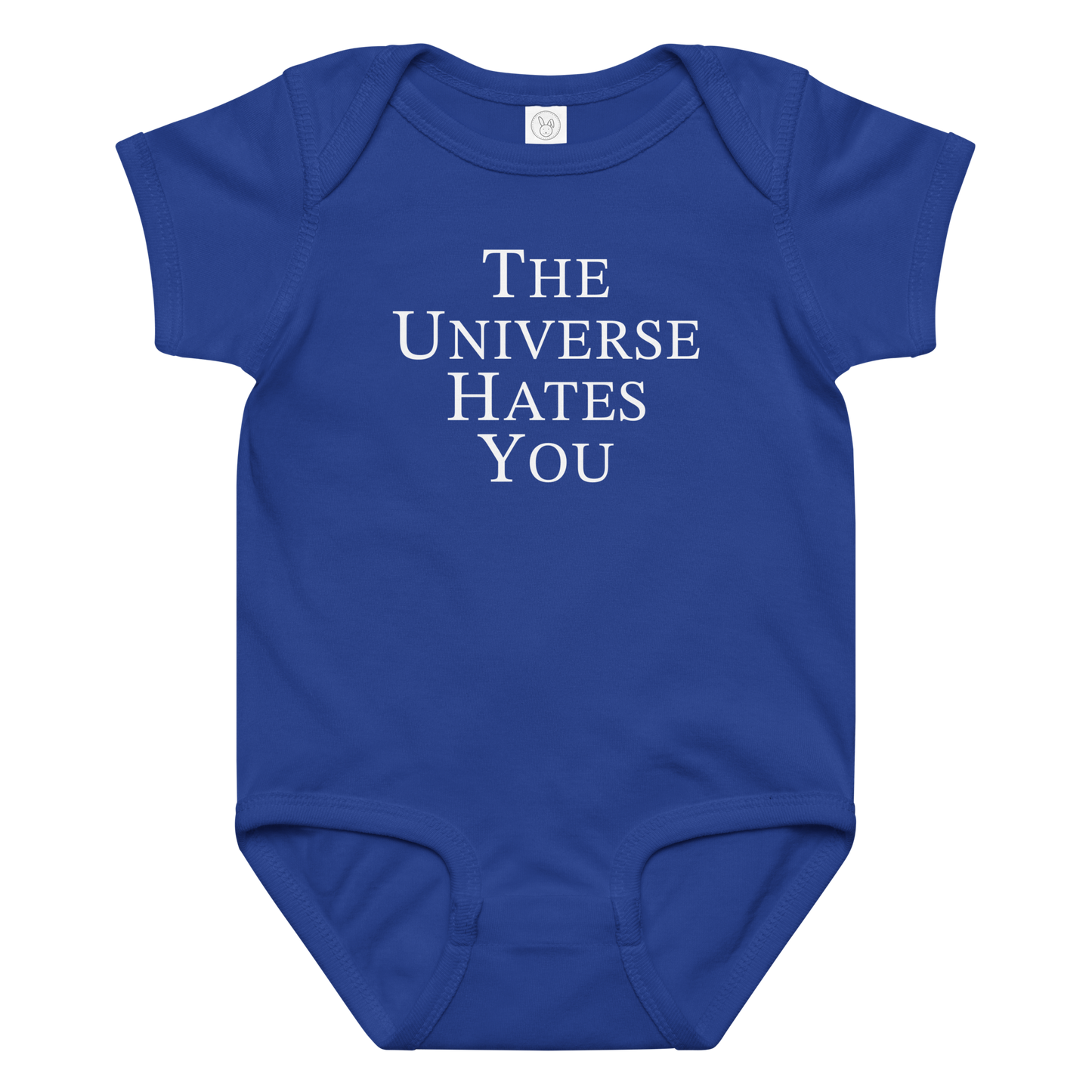 "The Universe Hates You" printed on a royal baby jersey bodysuit laying on a flat surface amongst other clothes