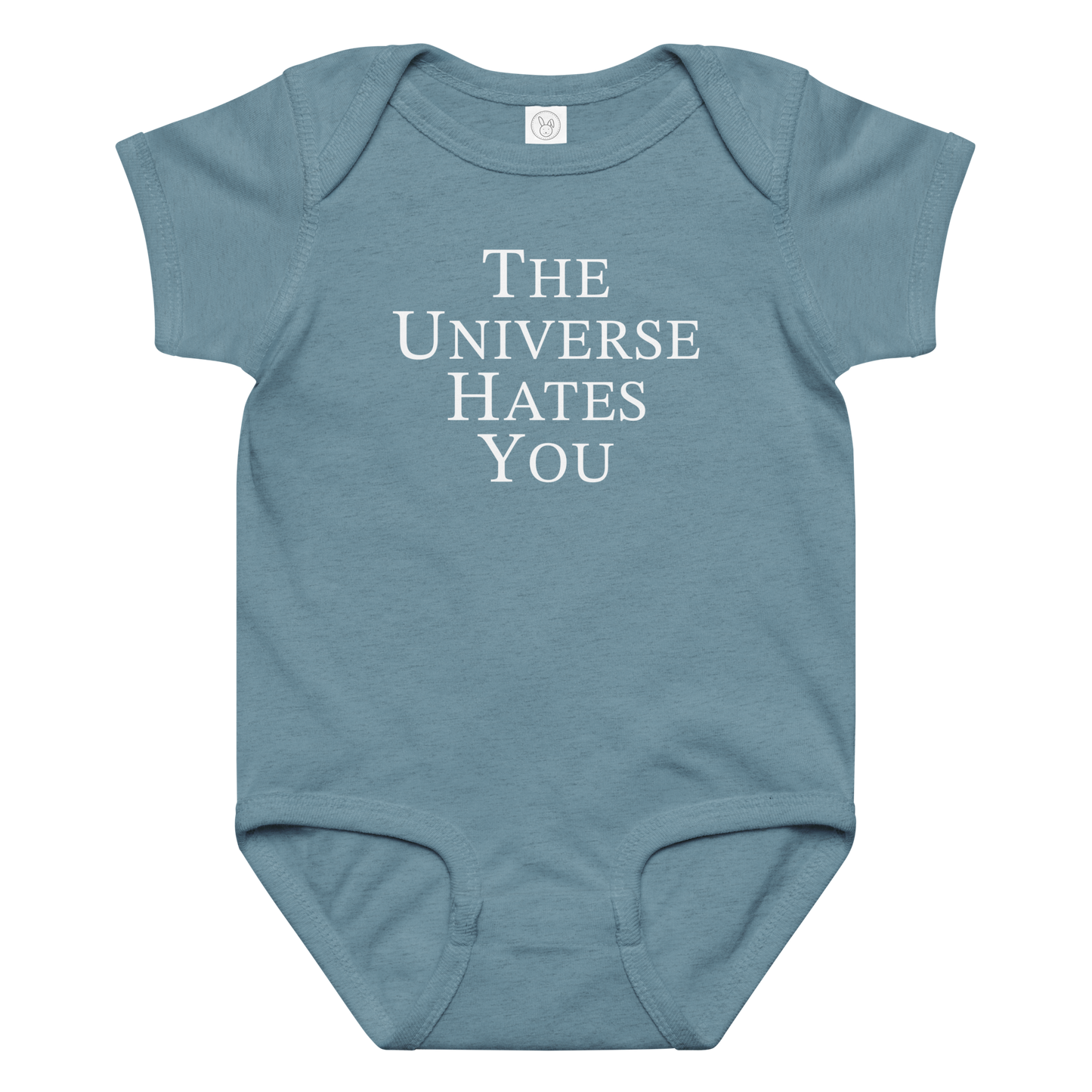 "The Universe Hates You" printed on a vintage indigo baby jersey bodysuit laying on a flat surface amongst other clothes
