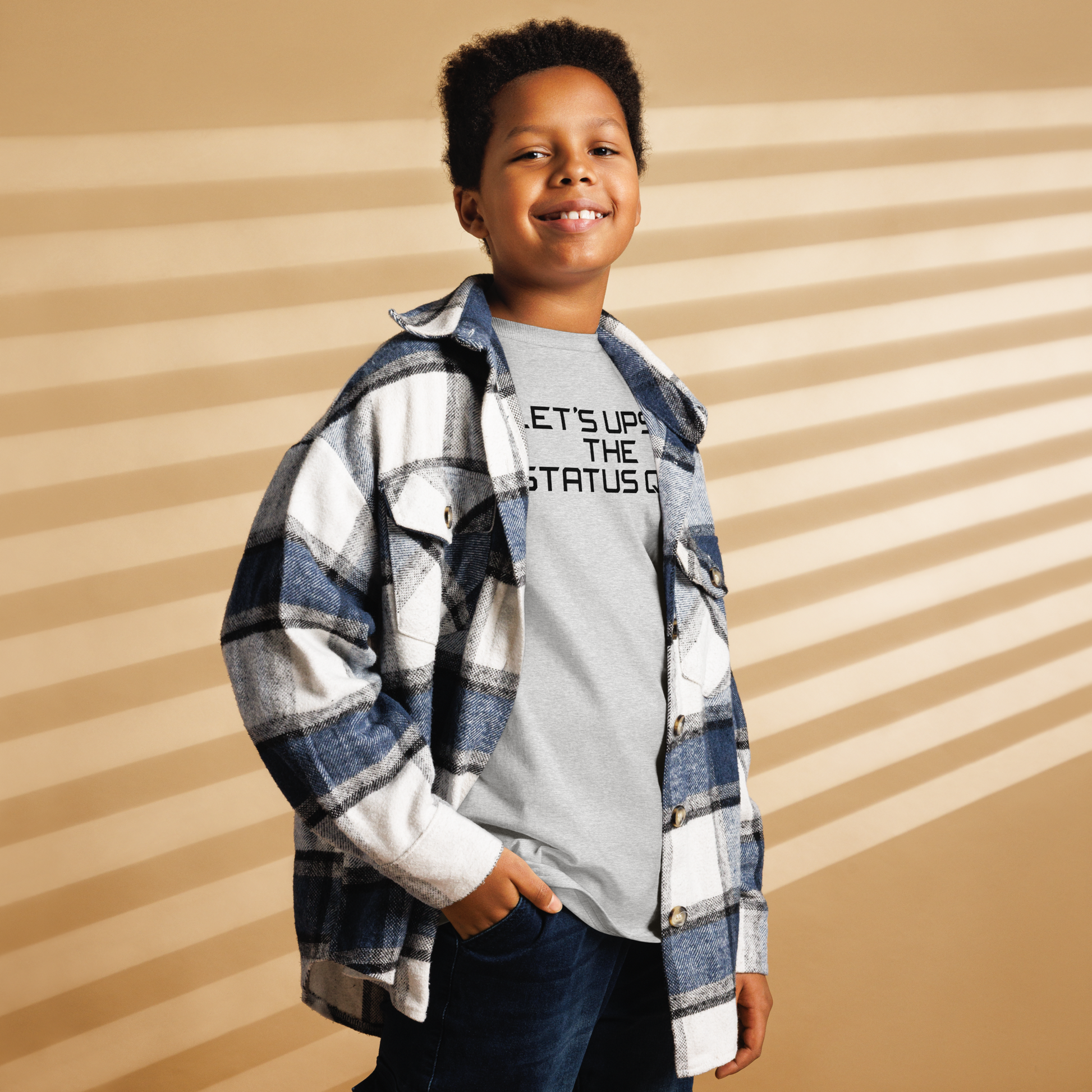 "Let's upset the status quo!" printed on a sport grey youth classic tee worn by a male also wearing a jacket