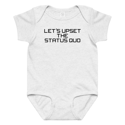 "Let's upset the status quo!" printed on a ash baby jersey bodysuit laying on a flat surface amongst other clothes