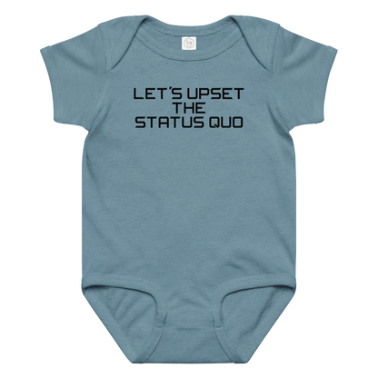 "Let's upset the status quo!" printed on a vintage indigo baby jersey bodysuit laying on a flat surface amongst other clothes