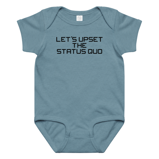"Let's upset the status quo!" printed on a vintage indigo baby jersey bodysuit laying on a flat surface amongst other clothes