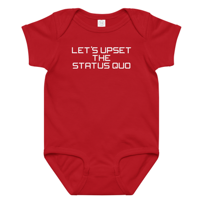 "Let's upset the status quo!" printed on a red baby jersey bodysuit laying on a flat surface amongst other clothes