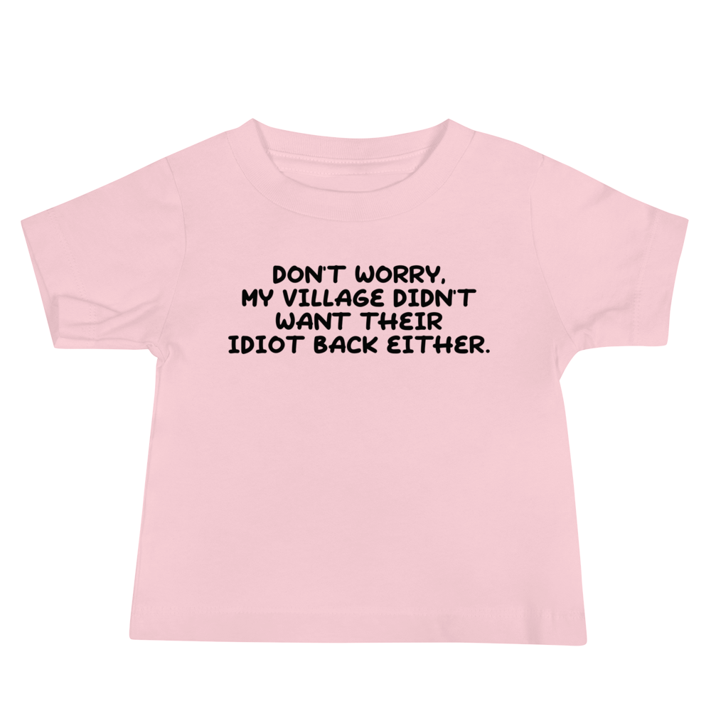 "Don't worry, my village didn’t want their idiot back either." printed on a pink baby jersey short sleeve tee laying on a flat surface