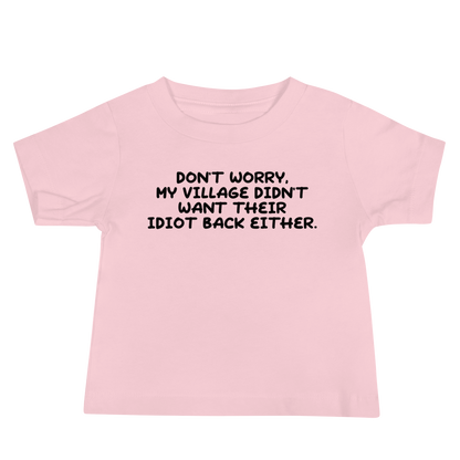 "Don't worry, my village didn’t want their idiot back either." printed on a pink baby jersey short sleeve tee laying on a flat surface