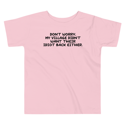 "Don't worry, my village didn’t want their idiot back either." printed on a pink toddler short sleeve tee laying on a flat surface