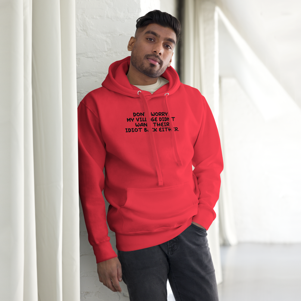 "Don't worry, my village didn’t want their idiot back either." printed on a team red unisex hoodie worn by a male