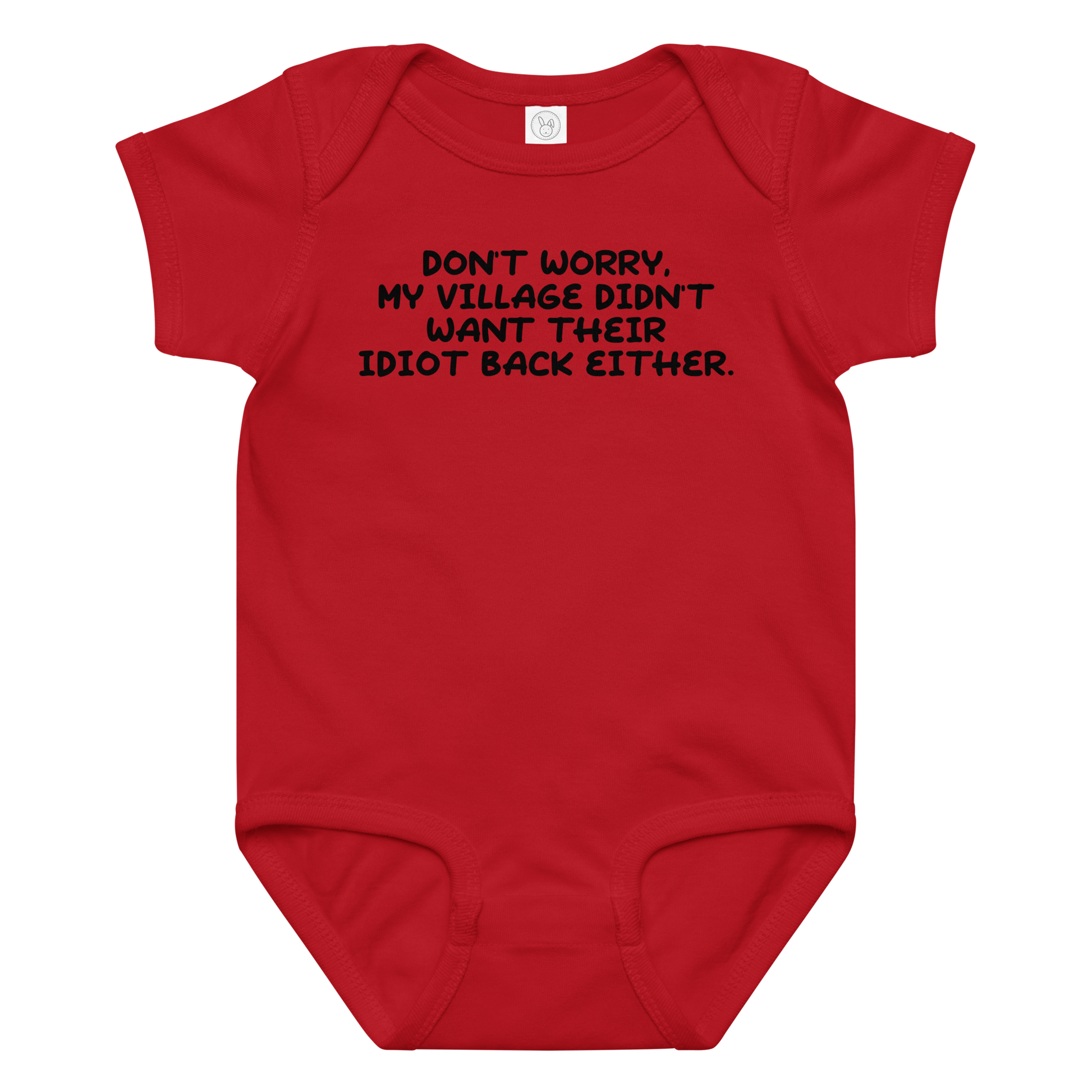 "Don't worry, my village didn’t want their idiot back either." printed on a red baby jersey bodysuit laying on a flat surface amongst other clothes