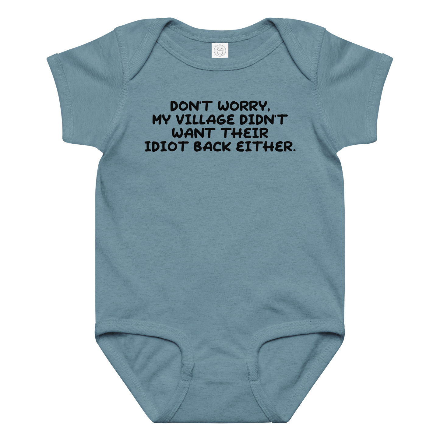 "Don't worry, my village didn’t want their idiot back either." printed on a vintage indigo baby jersey bodysuit laying on a flat surface amongst other clothes