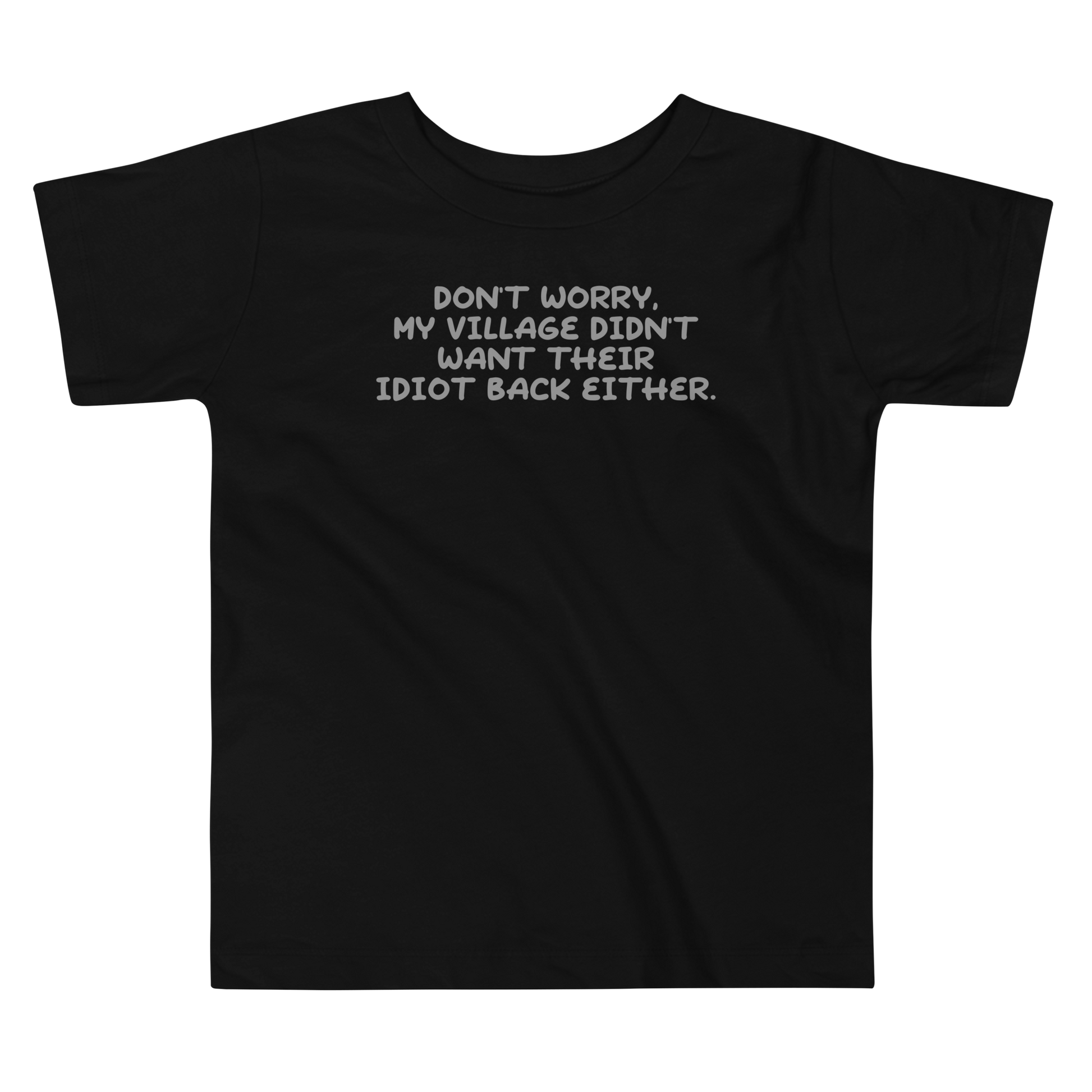 "Don't worry, my village didn’t want their idiot back either." printed on a black toddler short sleeve tee laying on a flat surface