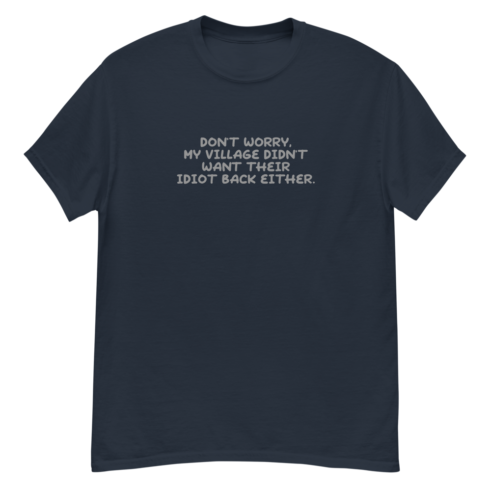 "Don't worry, my village didn’t want their idiot back either." printed on a navy unisex classic tee laying on a flat surface
