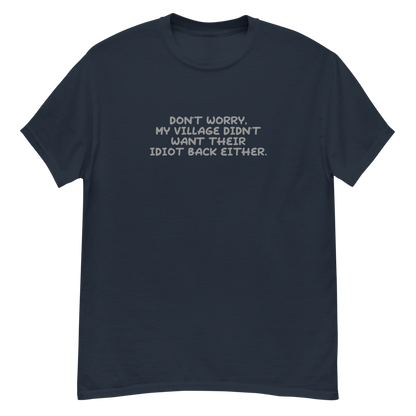 "Don't worry, my village didn’t want their idiot back either." printed on a navy unisex classic tee laying on a flat surface