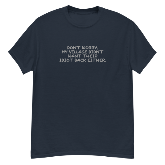 "Don't worry, my village didn’t want their idiot back either." printed on a navy unisex classic tee laying on a flat surface