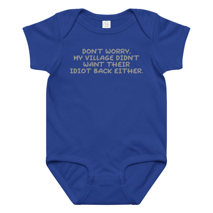 "Don't worry, my village didn’t want their idiot back either." printed on a royal baby jersey bodysuit laying on a flat surface amongst other clothes