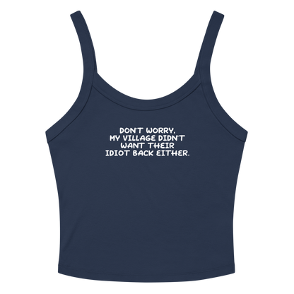 "Don't worry, my village didn’t want their idiot back either." printed on a solid navy blend women's micro-rib tanktop laying on a flat surface amongst sunglasses and shorts