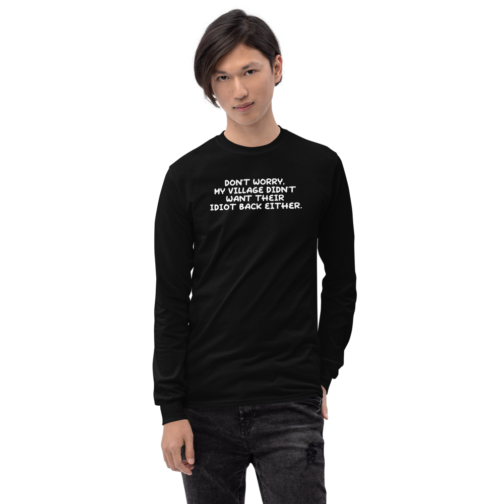 "Don't worry, my village didn’t want their idiot back either." printed on a black men's long sleeve shirt worn by a male