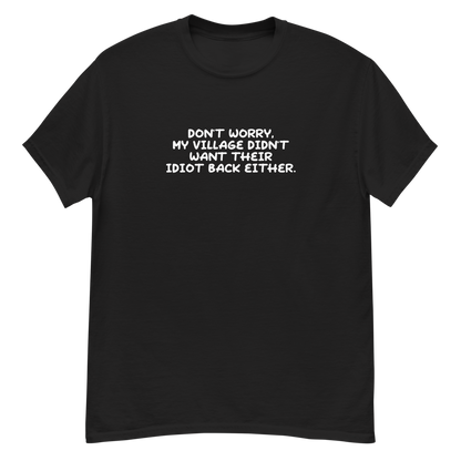 "Don't worry, my village didn’t want their idiot back either." printed on a black unisex classic tee laying on a flat surface