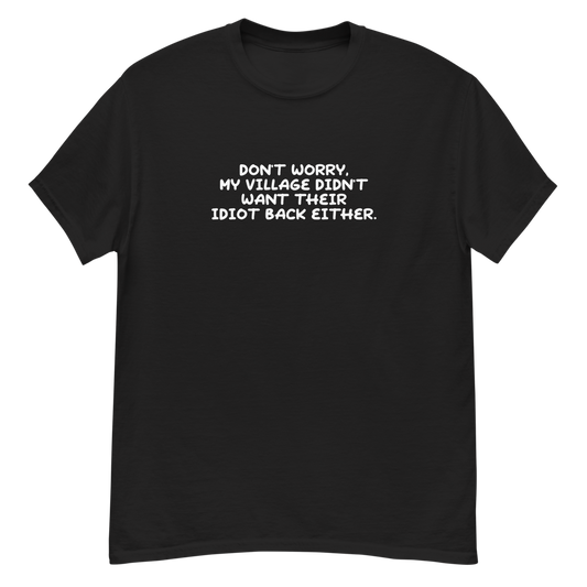 "Don't worry, my village didn’t want their idiot back either." printed on a black unisex classic tee laying on a flat surface