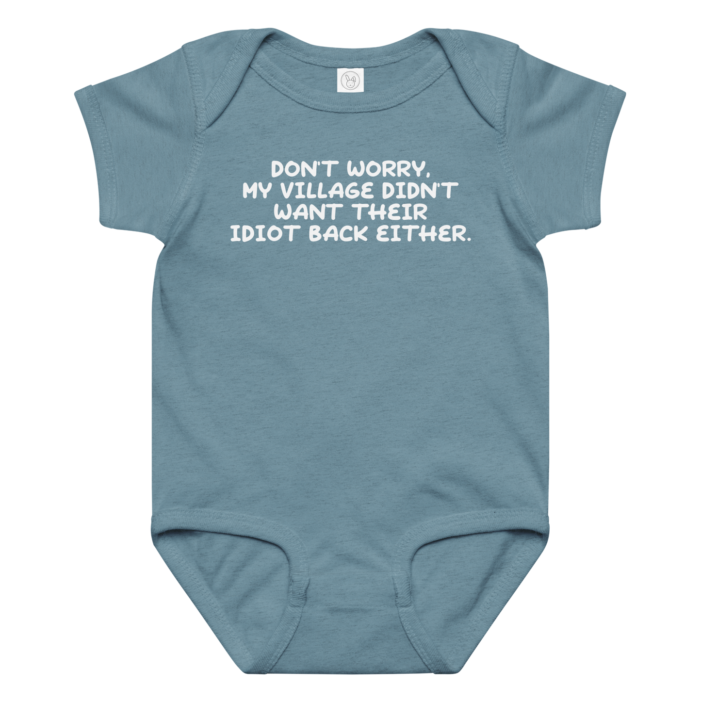 "Don't worry, my village didn’t want their idiot back either." printed on a vintage indigo baby jersey bodysuit laying on a flat surface amongst other clothes