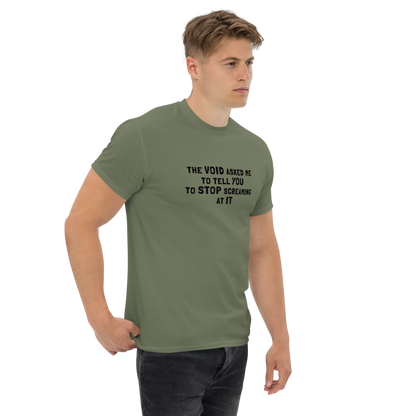 "The Void asked me to tell you to stop screaming at it" printed on a military green unisex classic tee worn by a male