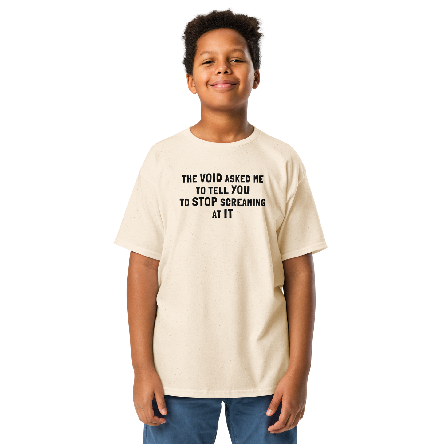 "The Void asked me to tell you to stop screaming at it" printed on a natural youth classic tee worn by a male