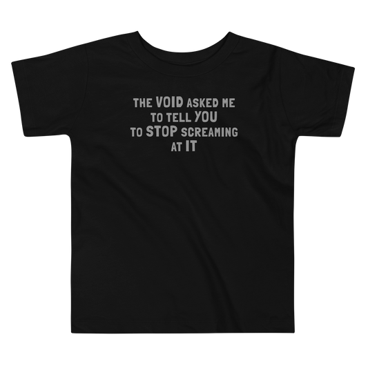 "The Void asked me to tell you to stop screaming at it" printed on a black toddler short sleeve tee laying on a flat surface